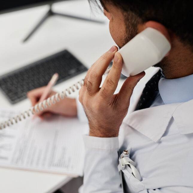 A medical staff talks on landline phone while writing notes on a clipboard — first opinion coverage from STAT