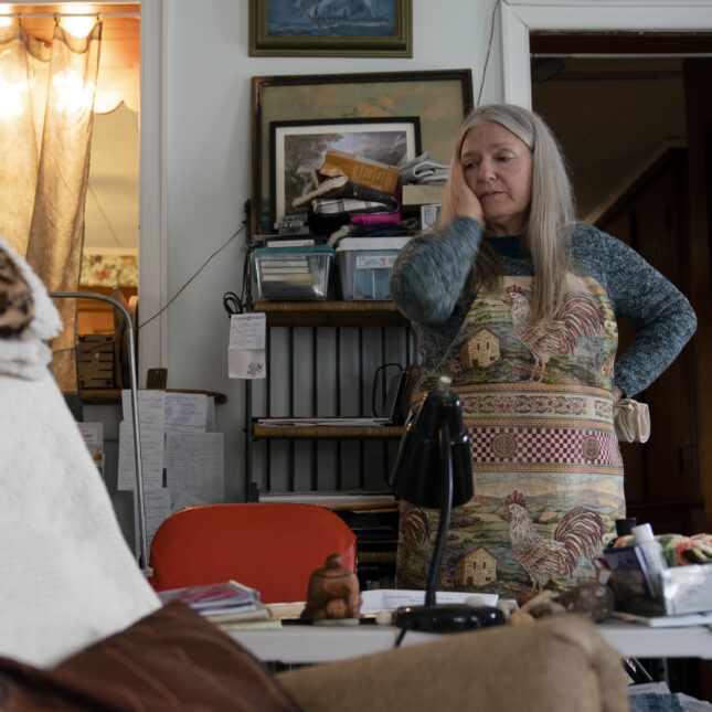 Nancy Rose rests head in her hands while organizing office space.